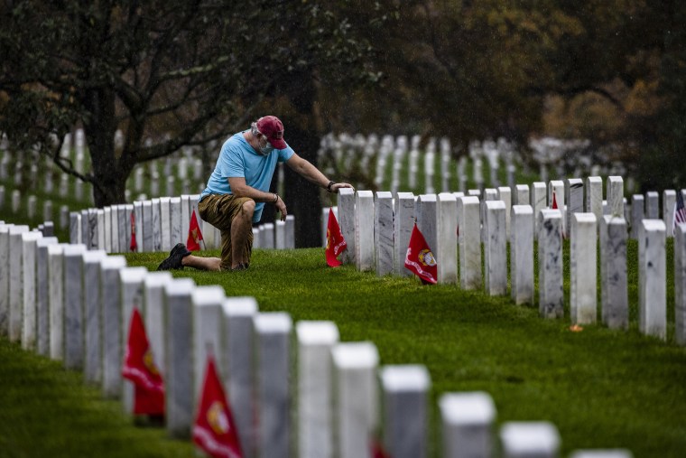 A man kneels in front of a fallen loved one at Arlington National Cemetery on Veterans Day, November 11, 2020 in Arlington, Virginia. Veterans Day is the day when the country honors those who served in the Armed Forces.