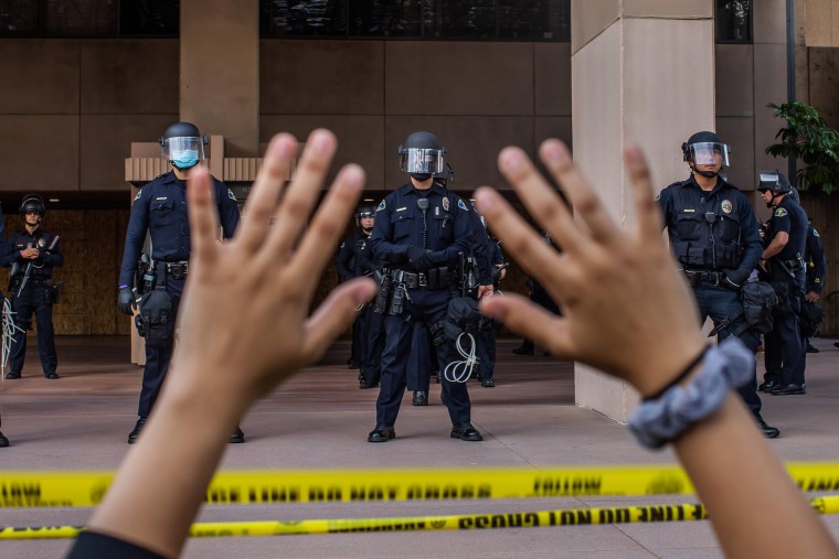 Image: A demonstrator holds her hands up while she kneels in front of the Police at the Anaheim City Hall on June 1, 2020 in Anaheim, California