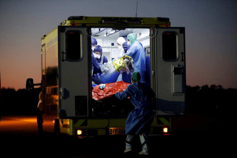 Image: Medical staff members load a patient on an ambulance in France's Vannes Airport.