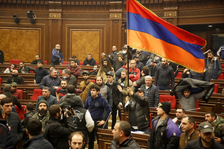 Image: Demonstrators with an Armenian national flag protest against an agreement to halt fighting over the Nagorno-Karabakh region, at the parliamentary building in Yerevan, Armenia