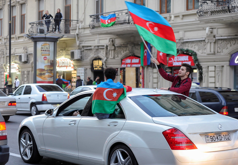 Image: People drive a car as they take part in celebrations in a street following the signing of a deal to end the military conflict over the Nagorno-Karabakh region in Baku, Azerbaijan