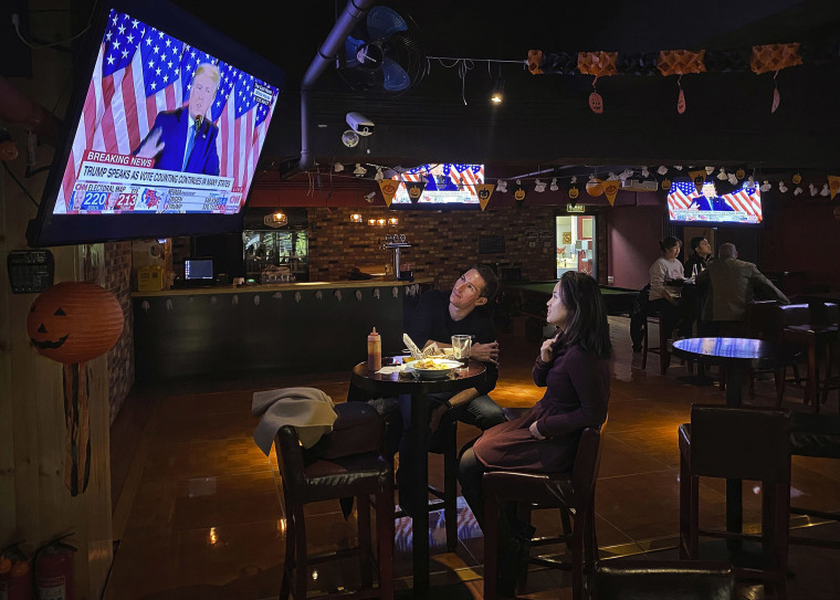 Image: Customers watch a speech by President Donald Trump on a television during an election watching event at a local bar
