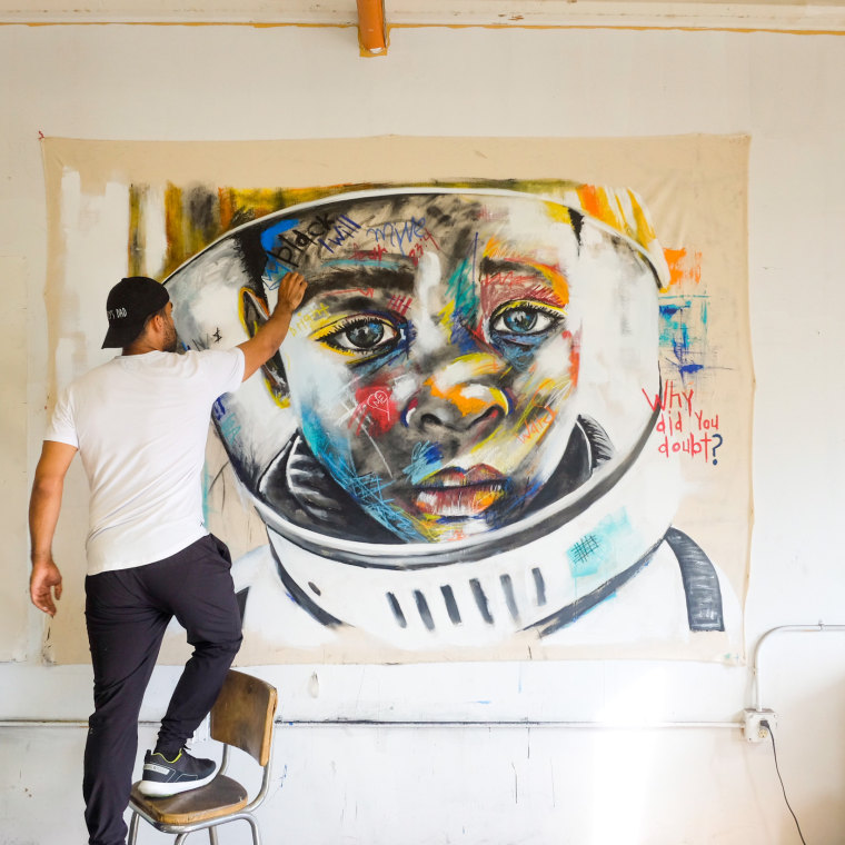 Image: Micah Johnson works on a painting called "Enlightened."