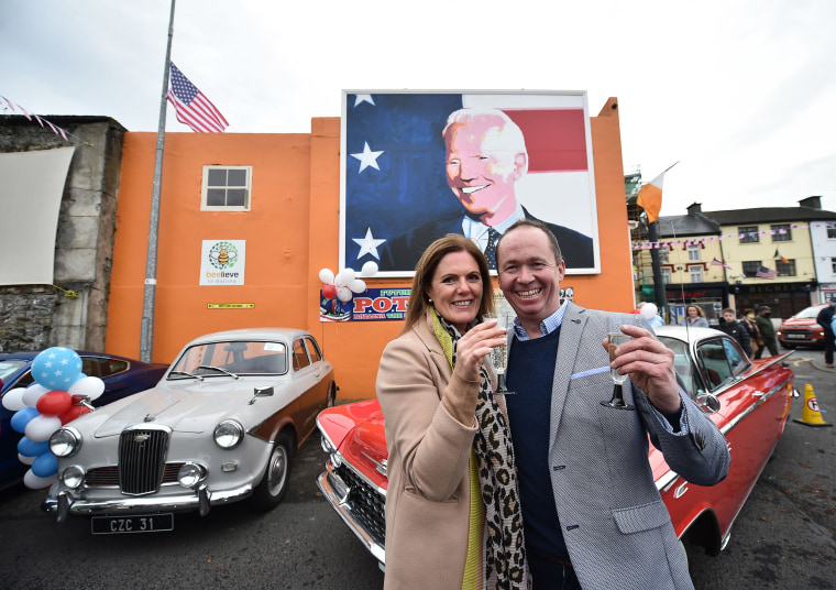 Image: Joe Blewitt and his wife Deirdre drink champagne underneath a mural of their third cousin Joe Biden as locals celebrate in anticipation of Joe Biden being elected as the next U.S. President