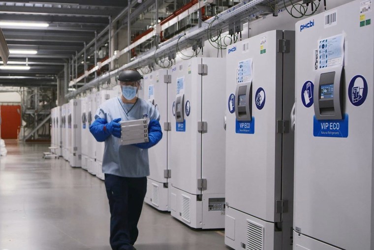 Image: A worker passes a line of freezers holding coronavirus disease vaccine candidate at a Pfizer facility in Puurs, Belgium.