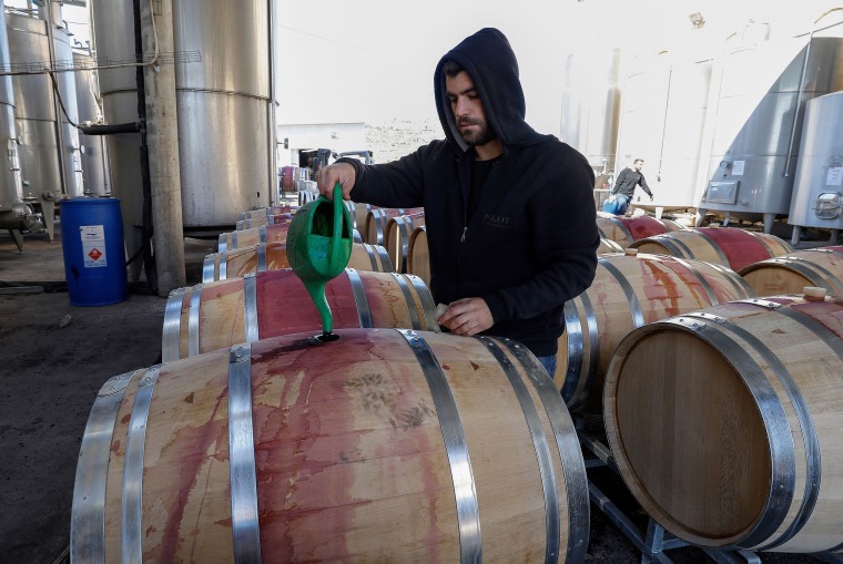 Image: A worker pours wine into a barrel at Psagot winery in the Israeli settlement of Psagot adjacent to the Palestinian West Bank city of Ramallah.