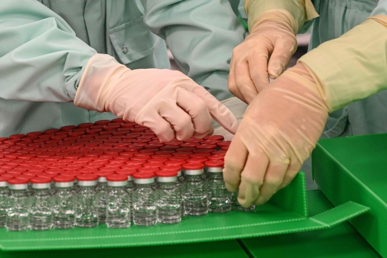 Image: Laboratory technicians handle capped vials as part of filling and packaging tests for the large-scale production and supply of the University of Oxfords COVID-19 vaccine candidate, AZD1222, conducted on a high-performance aseptic vial filling line.