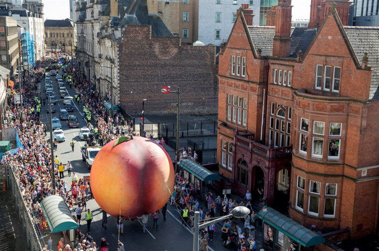 Members of the public gather to watch a giant peach during City of the Unexpected, a celebration of the author Roald Dahl in Cardiff, Wales, in 2016.