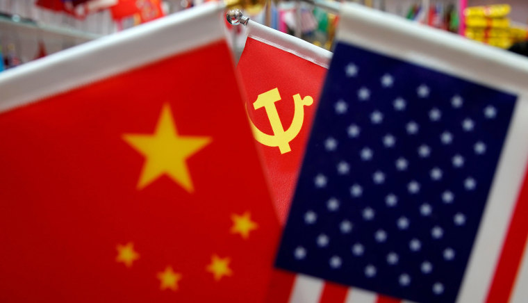 Image: The flags of China, the United States and Chinese Communist Party are displayed in a flag stall at the Yiwu Wholesale Market in Yiwu