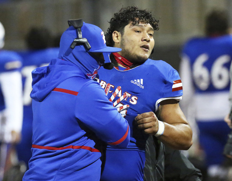 Image: Edinburg's Emmanuel Duron is pulled from the field by coaching staff after charging a referee during a high school football zone play-in game against Pharr-San Juan-Alamo