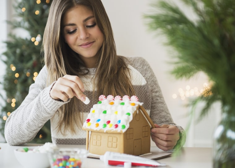 Young woman preparing gingerbread house