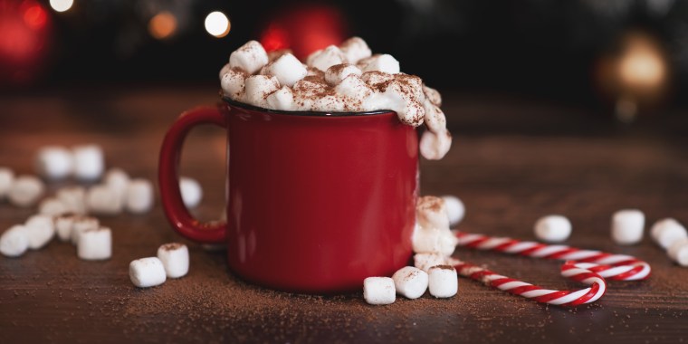 Winter whipped cream hot coffee in a red mug with star shaped cookies and warm scarf - rural still life