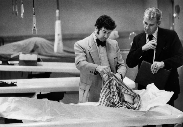 Image: Detectives go through the clothing of a murder victim