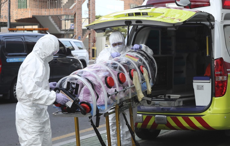 Image: Medial workers carry a patient infected with the coronavirus onto an ambulance at an elderly care facility in Ulsan, South Korea