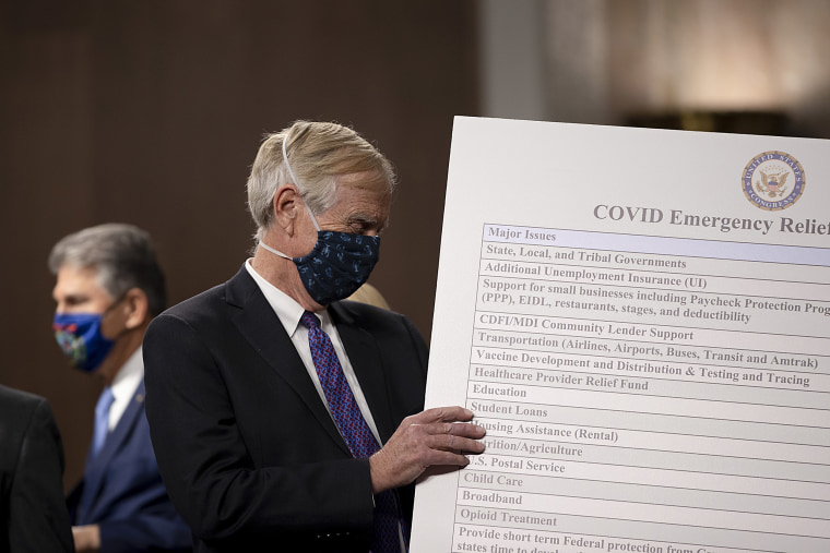 Image: Sen. Angus King (I-ME) sets up a sign  alongside a bipartisan group of Democrat and Republican members of Congress as they announce a proposal for a Covid-19 relief bill on Capitol Hill