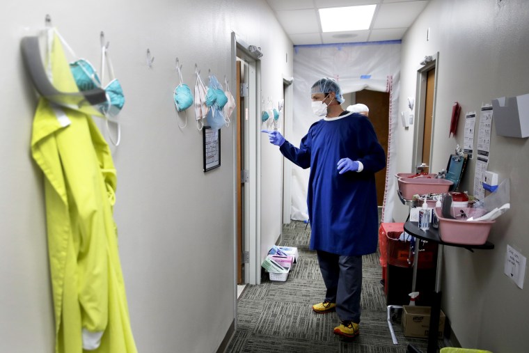 Dr. Drew Miller wears a homemade gown as he prepares to see potential Covid-19 patients on May 20, 2020, in an outpatient clinic at Kearny County Hospital in Lakin, Kan.