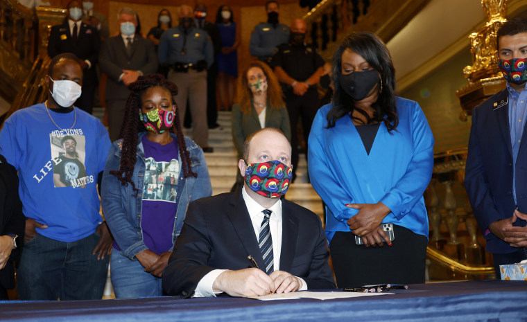 Colorado Governor Jared Polis signs a broad police accountability bill during a press conference in the rotunda of the State Capitol on June 19, 2020, in Denver. Looking on in back, from left, are Greg Bailey and Delisha Searcy, who lost their son, De'von Bailey, in a police shooting in August 2019 in Colorado Springs, Colo., Rep. Leslie Herod, D-Denver, and Senator Leroy Garcia, D-Pueblo.