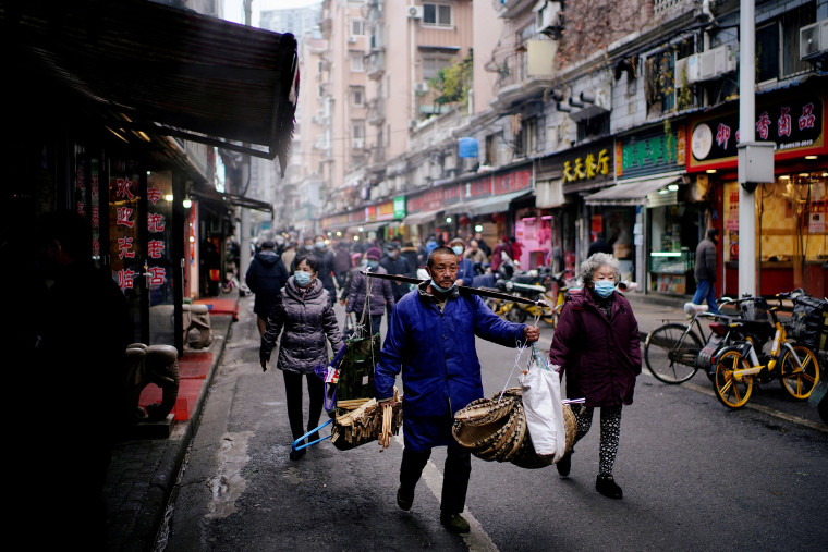 Image: People wearing protective masks walk at a street market almost a year after the start of the coronavirus disease (COVID-19) outbreak, in Wuhan, Hubei province