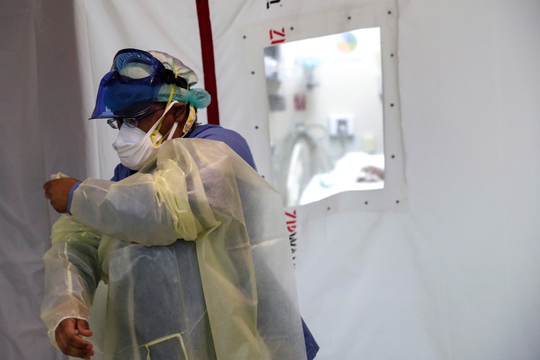 Image: Registered nurse Tamara Jones dresses in PPE outside an isolation room in the intensive care unit at Roseland Community Hospital on the South Side of Chicago