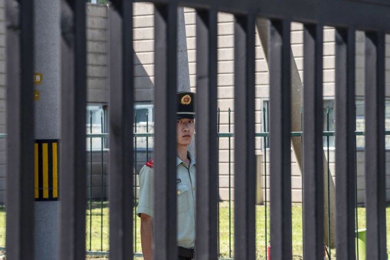 Image: A People's Armed Police officer stand guard behind a gate at the U.S. Embassy in Beijing, China.
