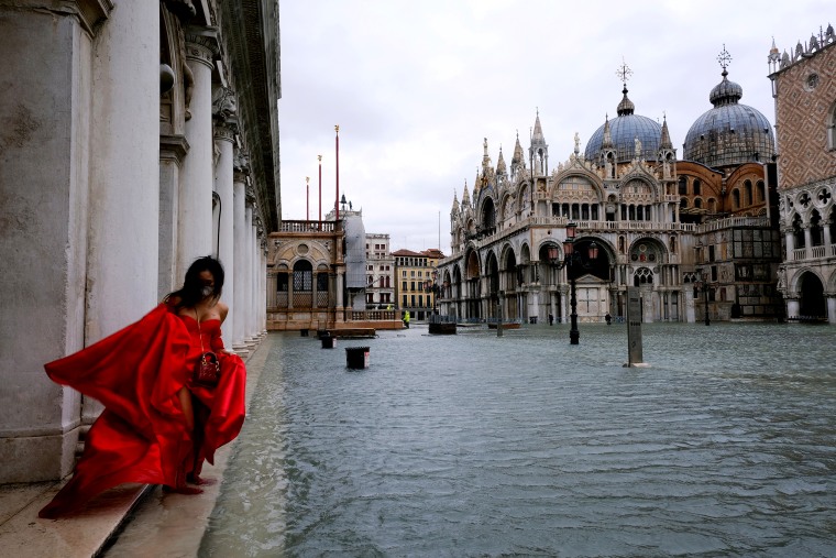 Image: A woman stands in flooded St. Mark's Square during high tide as the flood barriers known as Mose are not raised, in Venice