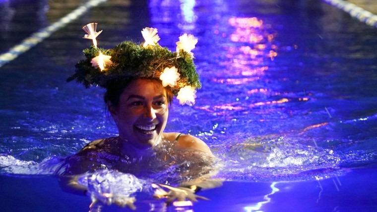 Image: Woman wearing a Christmas decorations headwear swims during a largest winter swimming relay in Tallinn