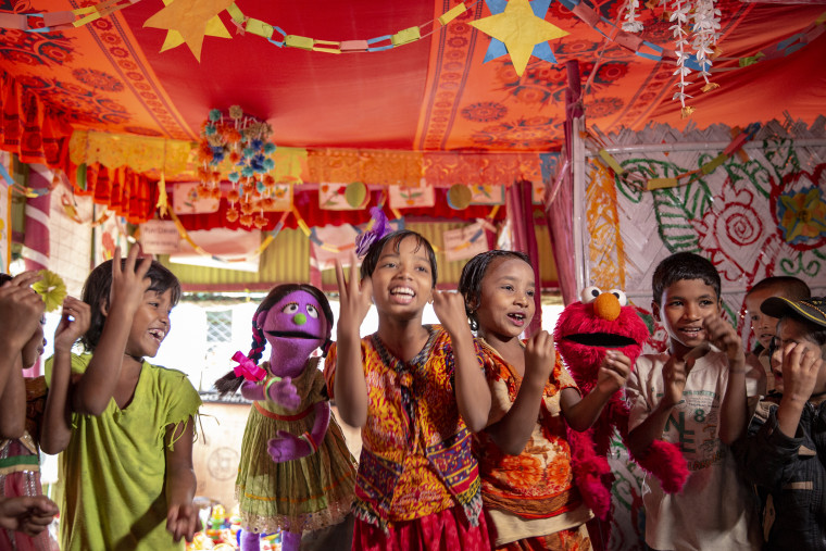 Tuktuki and Elmo sing and dance with Rohingya children in the Kutapalong camp in Cox's Bazar, Bangladesh.  There are over 700,000 Rohingya child refugees in the camp, growing up without access to a formal education.