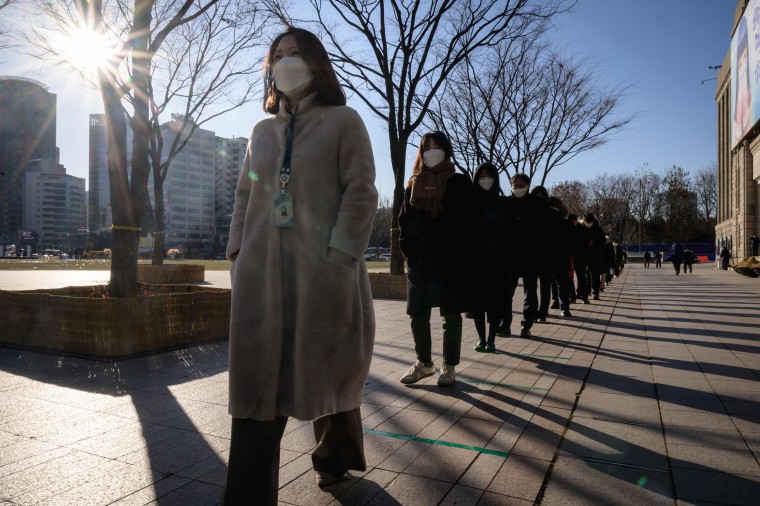 Image: Office workers and city government employees stand in line on Thursday for Covid-19 tests at a temporary testing center outside city hall in Seoul, South Korea.