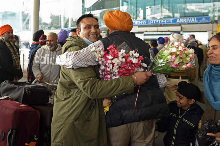 Image: A passenger arriving from the United Kingdom receives a hug after getting a Covid-19 coronavirus test at India's Sri Guru Ram Dass Jee International Airport