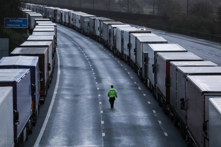 Image: A man walks past lorries parked on the M20 motorway near Ashford