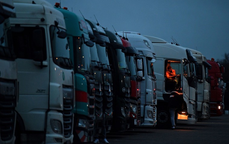 Image: Drivers of freight lorries and heavy goods vehicles are illuminated by the lights inside their cabs as they are parked at a truck stop off the M20 leading to Dover, near Folkestone in Kent, south east England