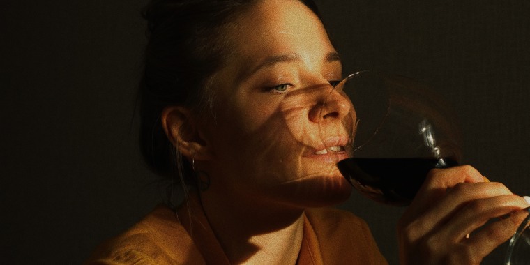 Close-Up Of Woman Drinking Wine Against Wall