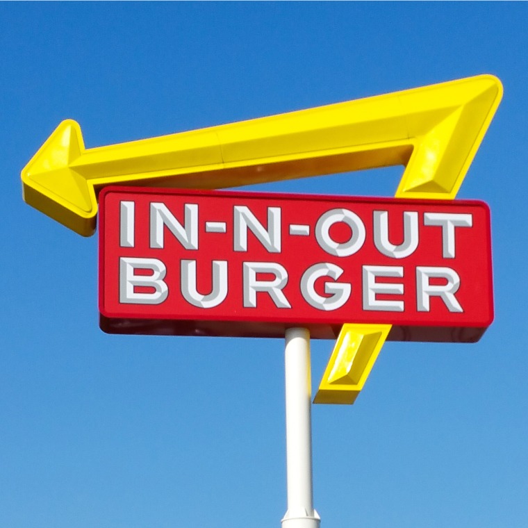 In-N-Out Burger Sign in parking lot with cars