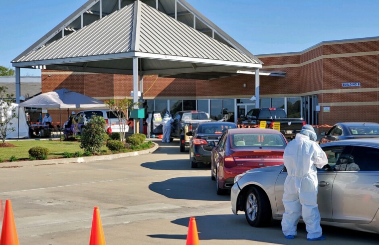 Image: A health care worker talks with a patient at the COVID-19 drive thru testing site at the Delta Health Center in Bolivar County