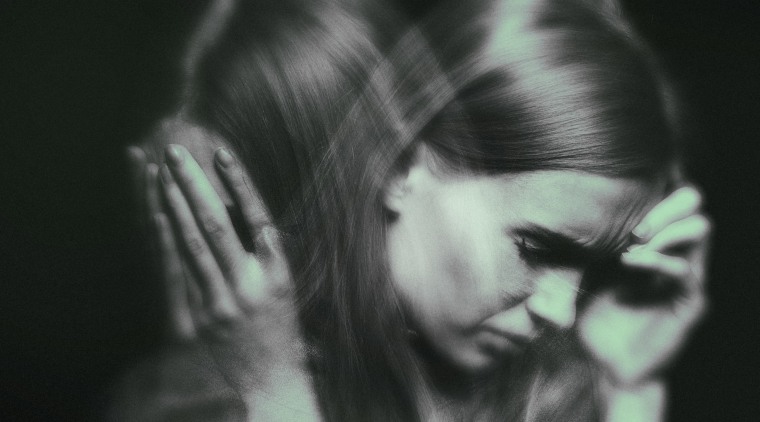 Image: A double exposure of a woman, stressed, with her head in her hands and subtle green overlay.