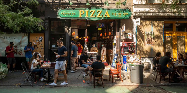 Pizza lovers practice social distancing at the al fresco dining outside the popular Prince Street Pizza in the Nolita neighborhood of New York on Sunday, August 23, 2020.