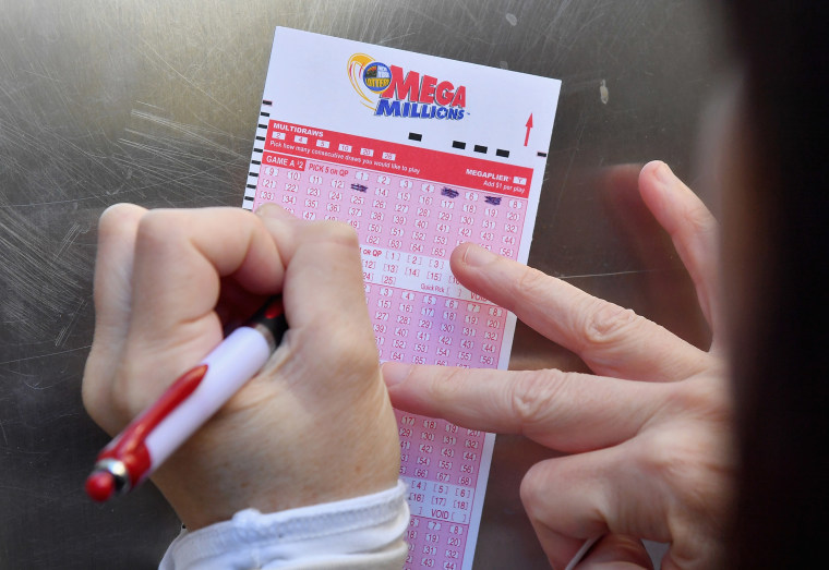 Image: A woman fills out a Mega Millions lottery ticket in New York City.