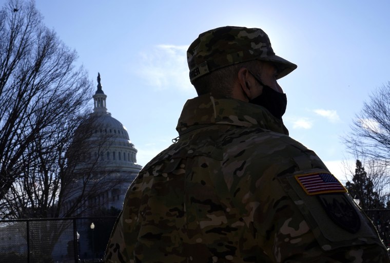Image: With the U.S. Capitol in the background, a member of the District of Columbia National Guard stands near newly-placed fencing around the Capitol grounds the day after violent protesters loyal to President Donald Trump stormed the U.S. Congress