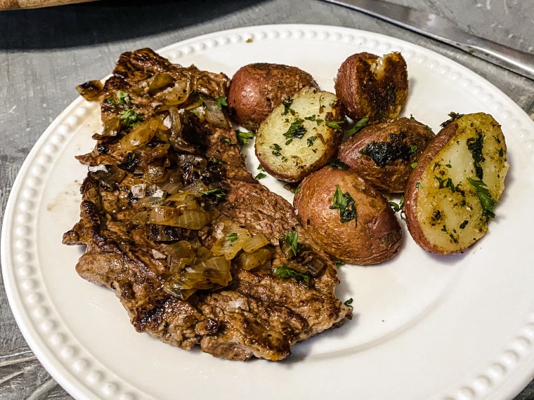 The final product: onion-marinated steaks served with red potatoes and parsley.