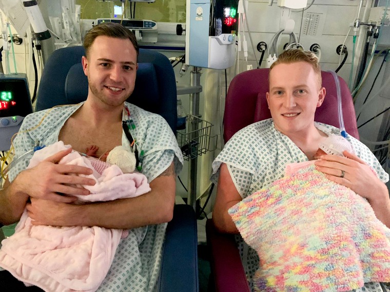 Ryan Morgan, 28, and his fiance Kyran Trodden, 25, hold their identical twin daughters, Skylar and Aria, shortly after their birth. The twins were carried by a surrogate mother.