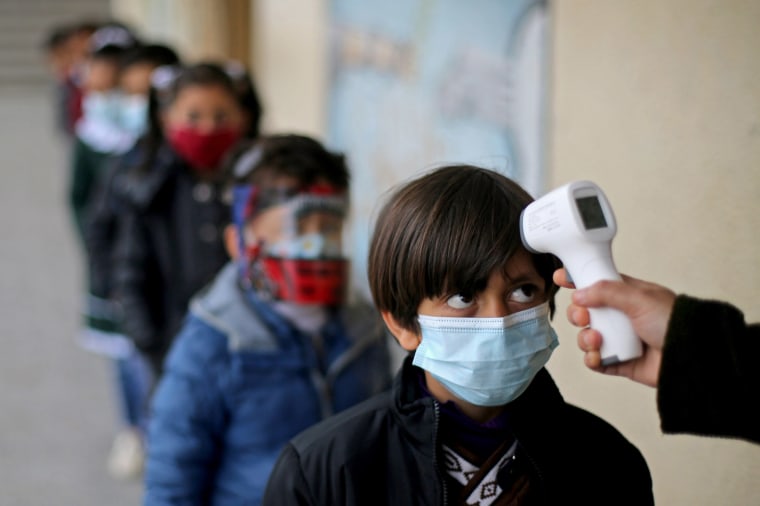 Image: A Palestinian student has his temperature checked as he enters his reopened school in the southern Gaza Strip