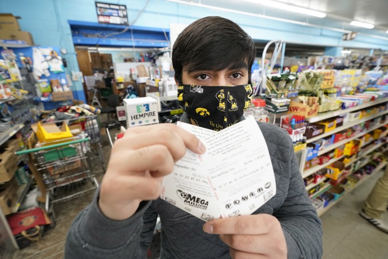 Image: Hardik Kalra, of Des Moines, Iowa, poses for a photo with his Mega Millions and Powerball lottery tickets