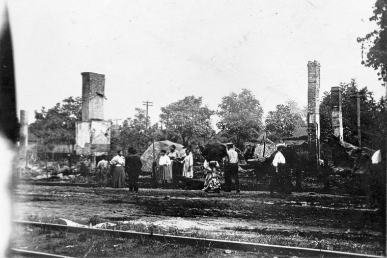 African-American residents standing near some of the residences burned during the race riot in Springfield, Ill., Aug. 1908.
