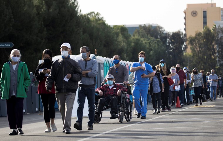 Image: People wait in line in a Disneyland parking lot to receive a dose of the Moderna COVID-19 at a mass vaccination site during the outbreak of the coronavirus disease (COVID-19), in Anaheim