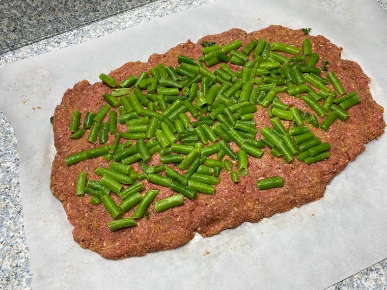 Before this meatloaf gets formed into a loaf, green beans get rolled into the center.