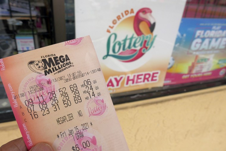 Image: A customer shows off a Mega Millions lottery ticket after purchasing it, Wednesday, Jan. 13, 2021, in Orlando, Fla.