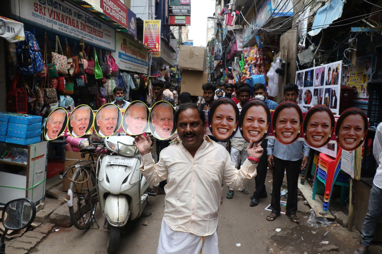Image: A man wears cut-outs of President-elect Joe Biden and Vice President-elect Kamala Harris and walks on a street in Chennai, India