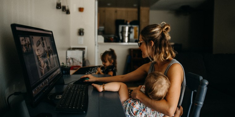 Working mother multitasking on the computer and holding baby