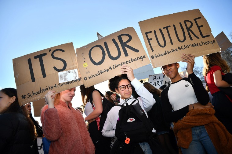 Image: Young demonstrators hold placards as they attend a climate change protest organised by "Youth Strike 4 Climate", opposite the Houses of Parliament in central London