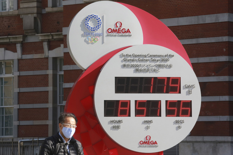Image: A man walks past a Tokyo Olympic and Paralympic Games countdown clock at the Tokyo train station in Tokyo